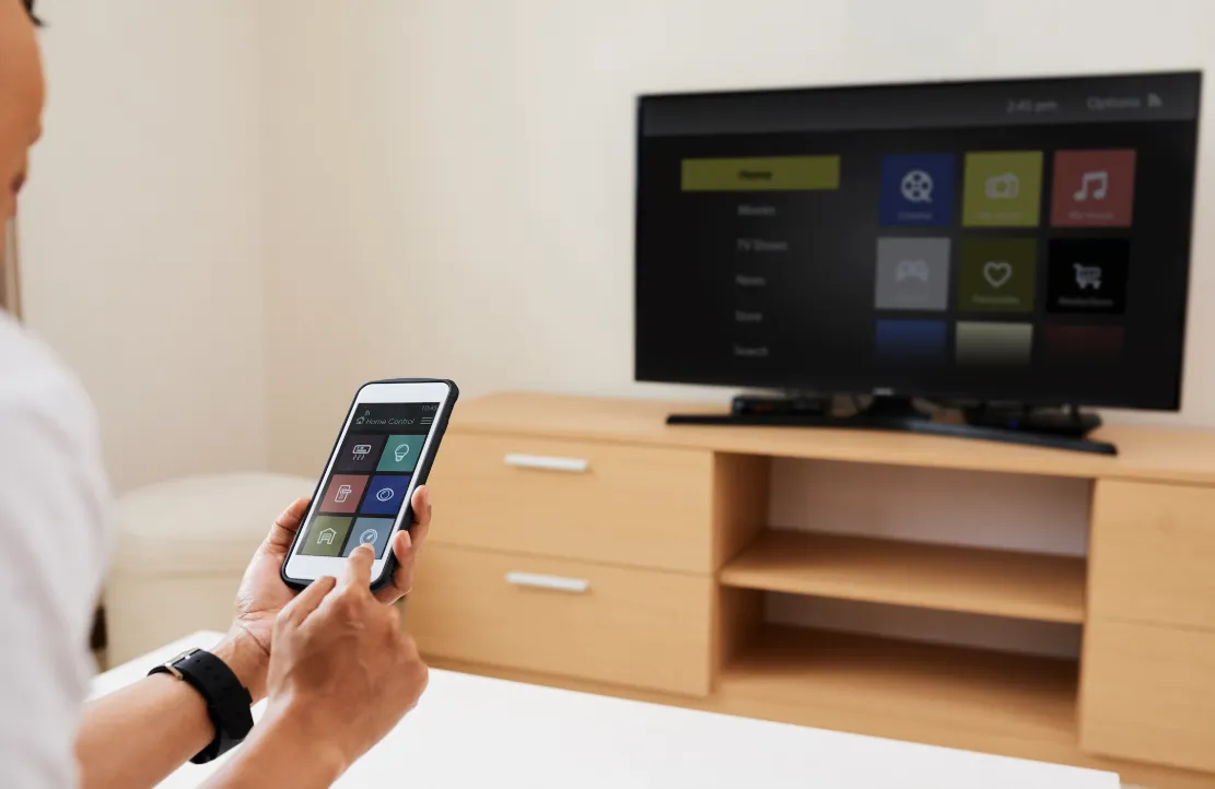 Person using a phone app to control a smart TV in a living room