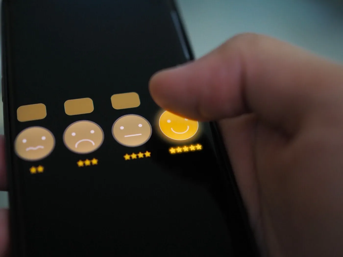 Finger tapping the five-star smiley on a rating scale on a phone screen